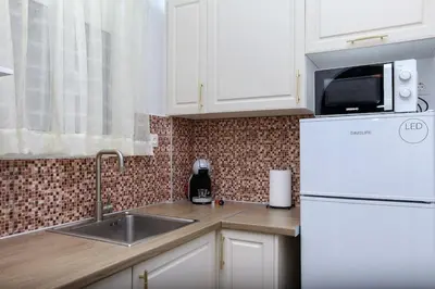 a white kitchen with a sink and a refrigerator at Evelyn's cozy house in Athens