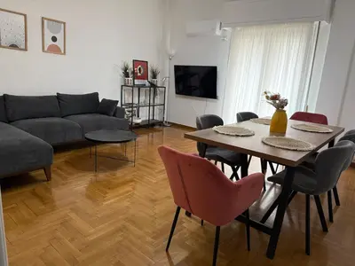a living room with a table and chairs and a couch at Athenian sunlit central flat! in Athens