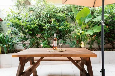 a wooden table with two wine glasses and an umbrella at Romantic Garden Central Rooftop Gym Fast Wifi in Athens
