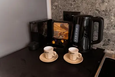 two coffee cups sitting on a counter with a coffee maker at Romantic Garden Central Rooftop Gym Fast Wifi in Athens