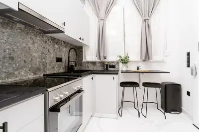 a kitchen with white cabinets and black counter stools at Romantic Garden Central Rooftop Gym Fast Wifi in Athens