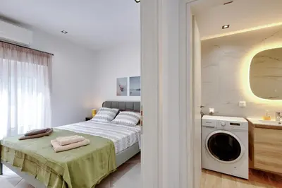 a bedroom with a bed and a washing machine at Suncity apartments with garden in Athens
