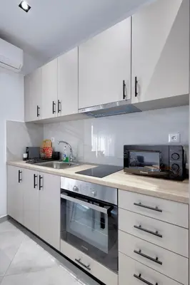 a kitchen with white cabinets and a microwave at Suncity apartments with garden in Athens