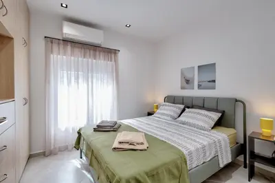 a white bedroom with a bed and a window at Suncity apartments with garden in Athens