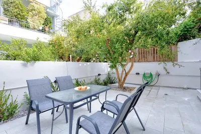 a patio with a table and chairs and a tree at Suncity apartments with garden in Athens