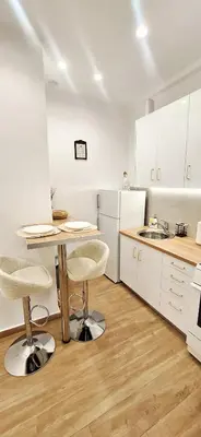 a kitchen with white cabinets and a table and chairs at Best Stay Athens Metro in Athens