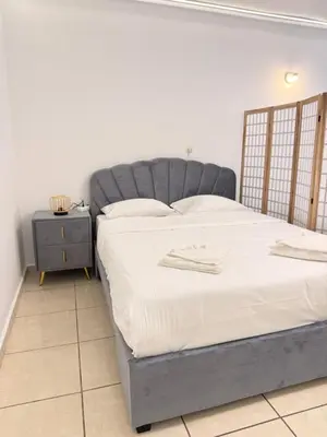 a bed with a gray headboard in a bedroom at Cozy studio 10minutes from airport in Markopoulo