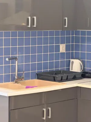 a kitchen with a sink and a blue tiled wall at Cozy studio 10minutes from airport in Markopoulo