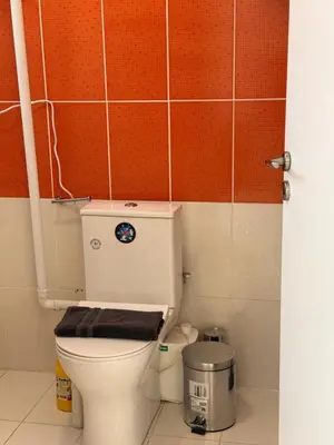 a bathroom with a toilet with a brown tile wall at Cozy studio 10minutes from airport in Markopoulo