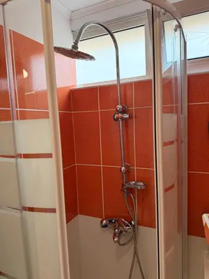 a shower in a bathroom with red tile at Cozy studio 10minutes from airport in Markopoulo