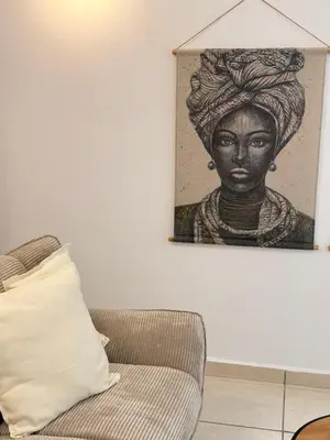 a painting of a woman on a wall next to a couch at Cozy studio 10minutes from airport in Markopoulo