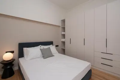 a bedroom with a white bed and a white cabinet at Stylish 4BR Top Floor w Private Rooftop Lounge in Athens