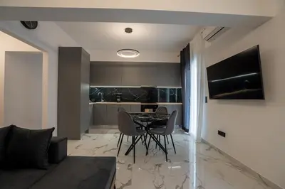 a living room with a table and chairs and a kitchen at Athenian Hospitality in Athens