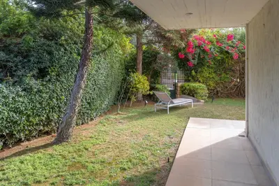a patio with a chair and a hedge with pink flowers at Private Garden Duplex in Voula by GHH in Athens