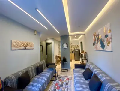 a living room with couches and a clock on the wall at Athens Victoria's Family Apartment in Athens