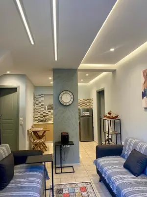 a living room with two couches and a clock on a wall at Athens Victoria's Family Apartment in Athens