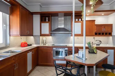 a kitchen with wooden cabinets and a table with chairs at Luxury Apartment in Glyfada with Sea View in Athens