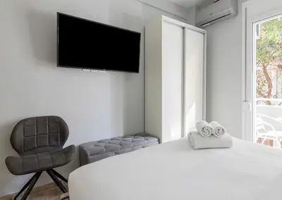 a bedroom with a bed and a chair and a television at Voulis Apartment 2 in Athens
