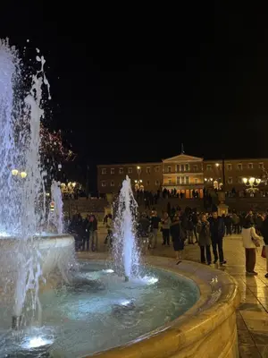 a fountain with people standing around it at night at Voulis Apartment 2 in Athens