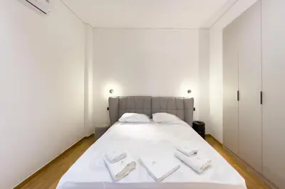 a bedroom with a white bed with two white towels on it at AtheNeon Deluxe Suite in Athens