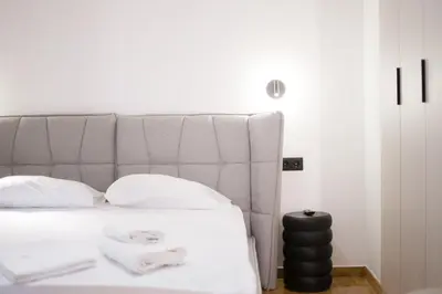 a bed with a gray headboard and white pillows at AtheNeon Deluxe Suite in Athens