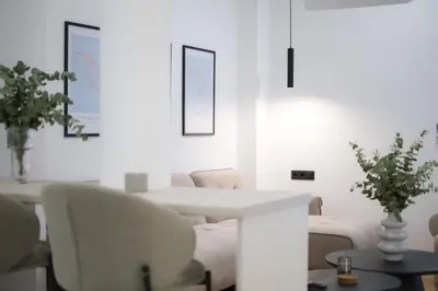 a white dining room with a white table and chairs at AtheNeon Deluxe Suite in Athens