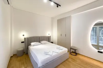 a white bedroom with a bed and a window at AtheNeon Deluxe Suite in Athens