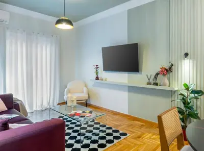 a living room with a couch and a tv on a wall at Urban Blush Pangrati by Premium Key in Athens