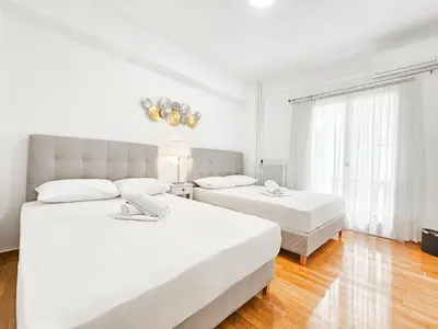 a white bedroom with two beds and a window at Casa Divas Galaxy Suite in Athens