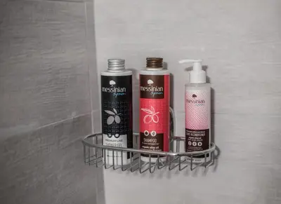 a bathroom rack with three bottles of hair products at ANDIE Kallithea Apartment in Athens