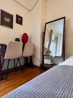 a bedroom with a bed and two chairs and a mirror at Lycabettus Elia in Athens