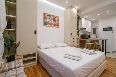 a bedroom with a large white bed and a kitchen at The Honeycomb Suite in Athens