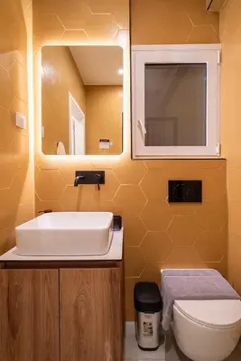 a bathroom with a sink and a toilet and a mirror at The Honeycomb Suite in Athens