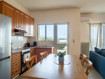 a kitchen with a wooden table and a dining room at Athens Airport Luxury Apartment in Spáta