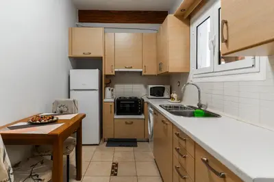 a kitchen with wooden cabinets and a white refrigerator at Sweet home in Athens