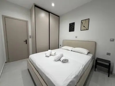 a bedroom with a large white bed with towels on it at Urban Comfort Apartment in Athens