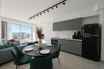 a kitchen and living room with a table and green chairs at Costa Elliniko Pool & Beach Sea View DA1 in Athens