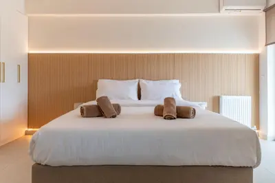 a large white bed with two brown towels on it at La Suite by A&D Properties in Porto Rafti