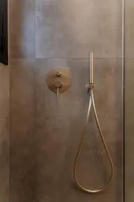 a shower with a shower head on a wall at 1BR Designer Suite Homey Feel Near Metro in Athens