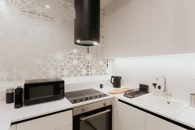 a white kitchen with a stove top oven next to a sink at 1BR Designer Suite Homey Feel Near Metro in Athens