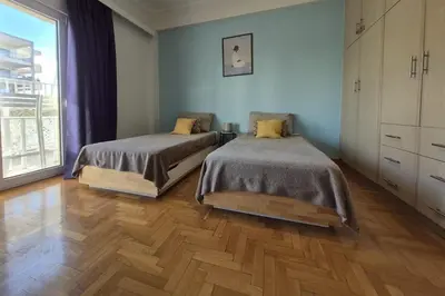 two beds in a room with wooden floors at Athens Riviera Alimos by Comfort Club in Athens