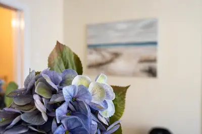 a vase filled with purple flowers in front of a painting at Athens Unity Apartment in Athens