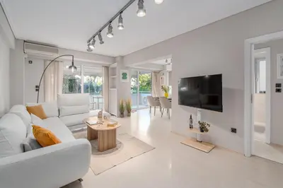 a living room with a white couch and a tv at Coastal Serenity - Glyfada Central - Lampraki 6 by K&M in Athens