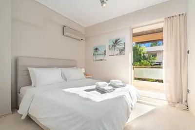 a white bedroom with a bed and a large window at Coastal Serenity - Glyfada Central - Lampraki 6 by K&M in Athens