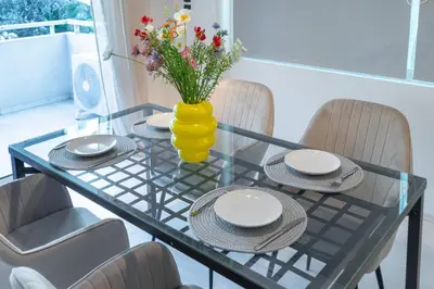 a glass table with chairs and a vase with flowers at Coastal Serenity - Glyfada Central - Lampraki 6 by K&M in Athens