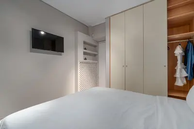 a bedroom with a white bed and a tv at Coastal Serenity - Glyfada Central - Lampraki 6 by K&M in Athens
