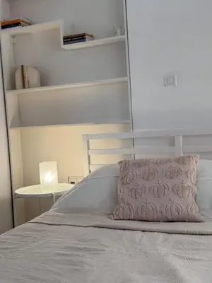 a bed with a pink pillow on top of it at Parmen APT in Piraeus