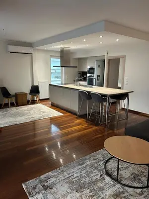 a living room with a table and a kitchen at Glyfada Top-Floor 2BR, Sea and City Views in Athens
