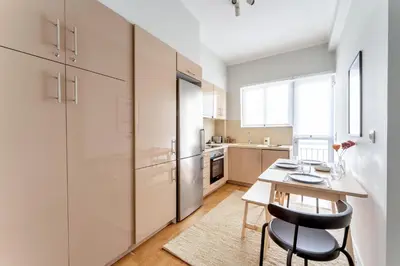 a kitchen with white cabinets and a table and chairs at Urban Grace - In the Heart of Athens in Athens