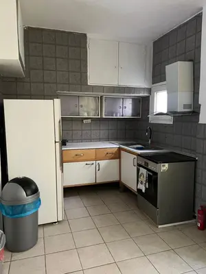 a small kitchen with white cabinets and a refrigerator at Athenian Maisonette near Metro & shops in Athens
